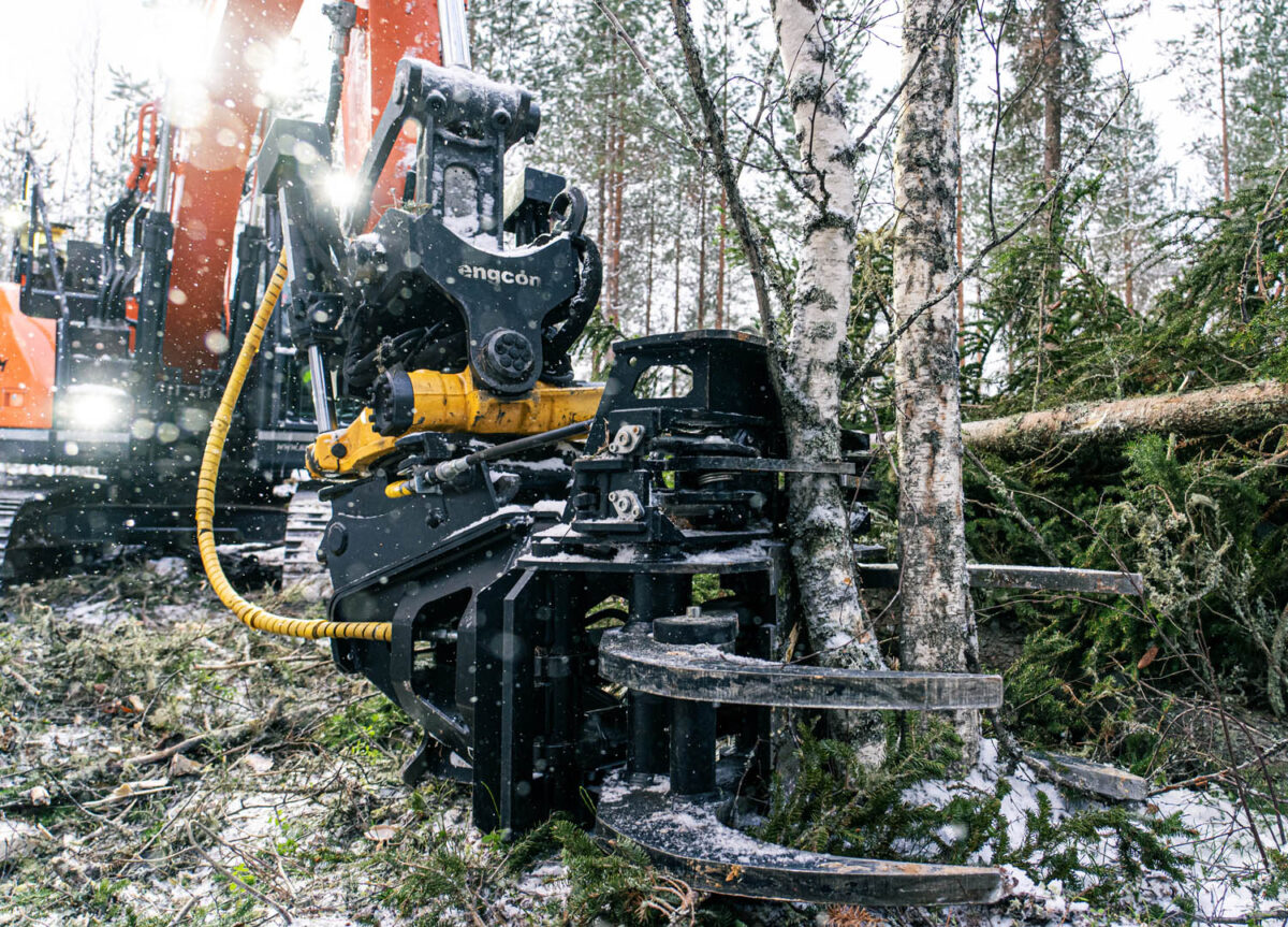 JAK energiakoura kiinnitettynä kaivinkoneeseen leikkaamassa puita metsässä.