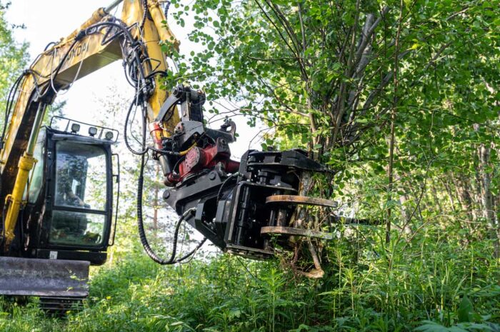 JAK-250R energiakoura joukkokeräimellä kiinnitettynä kaivinkoneeseen, leikkaamassa puita tehokkaasti.