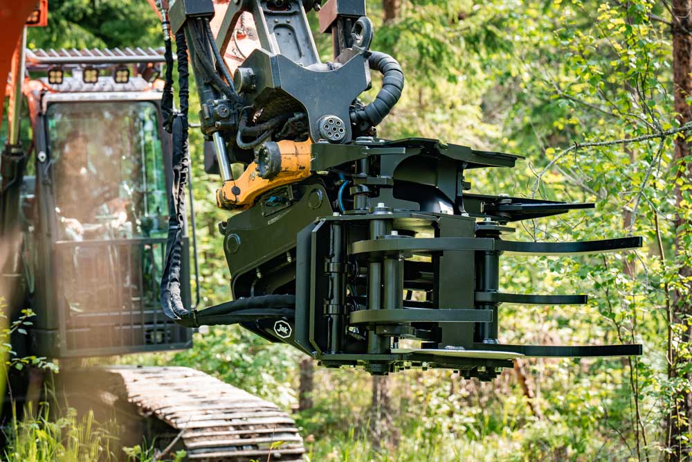 JAK-300B energiakoura asennettuna kaivinkoneeseen metsässä, tehokas puiden kaatamiseen ja raivaustöihin.